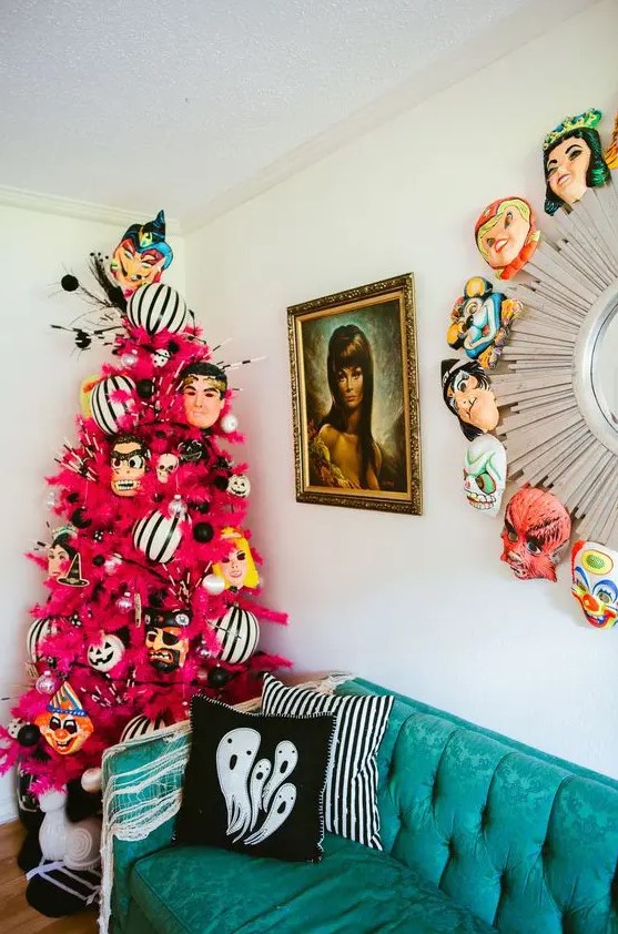 a neon pink Halloween tree decorated with monster masks and black and white oversized ornaments is adorable