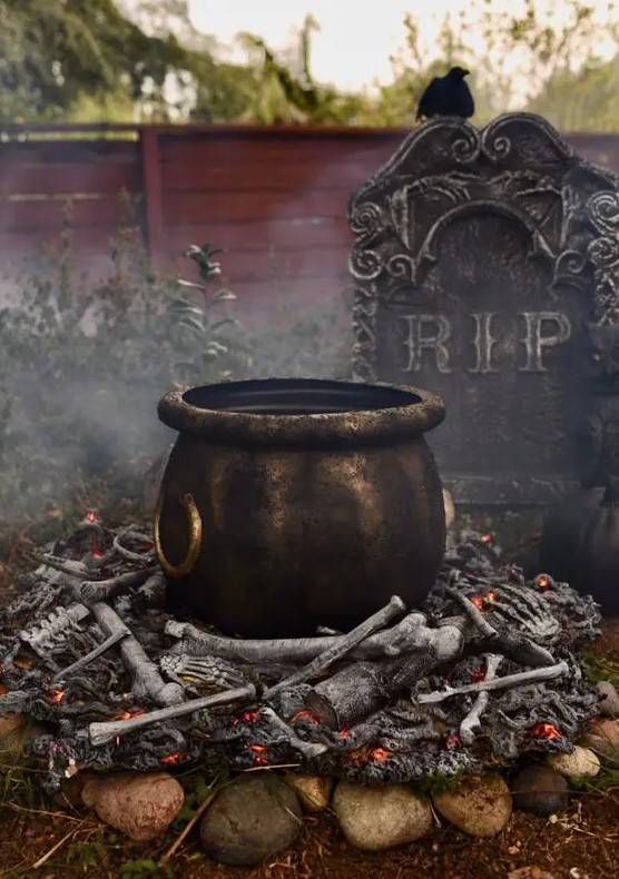 a realistic and scary witches' cauldron placed on bones is a lovely outdoor decoration for Halloween
