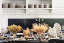 27 a stylish modern Thanksgiving tablescape with taupe napkins and table runners, wheat in vases, turkeys, candles and gold cutlery