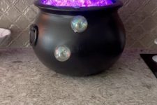 29 a witch’s cauldron with neon purple bubbles is a fun and cool idea to decorate your kitchen or bar cart for Hallwoeen