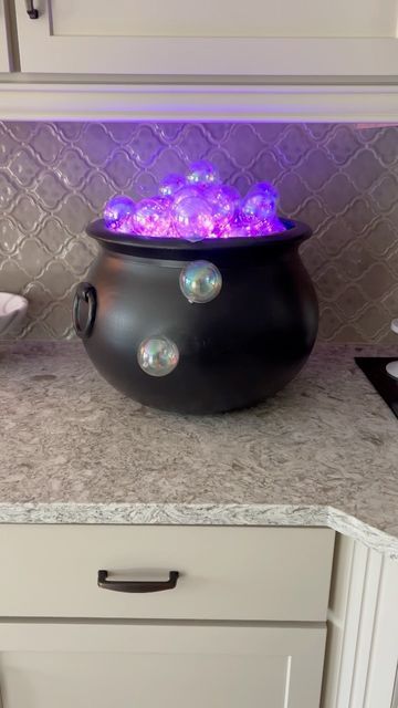 a witch's cauldron with neon purple bubbles is a fun and cool idea to decorate your kitchen or bar cart for Hallwoeen