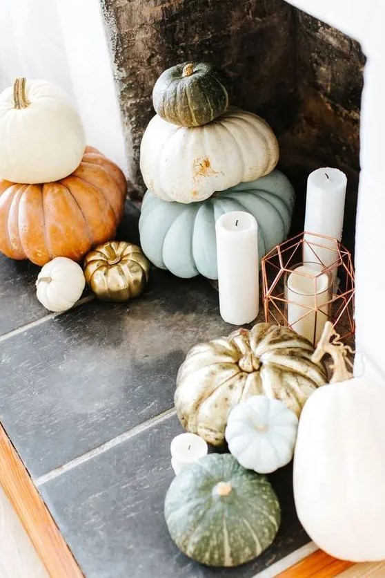 a fall or Thanksgiving fireplace with stacked heirloom pumkins and pilalr candles in lanterns and without them