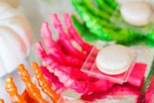 30 bold neon skeleton hands holding desserts are a cool and bold idea for a Halloween neon party
