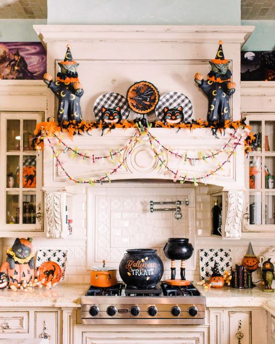 fun and bold Halloween decor in black and orange, with black catds, cauldrons, pumpkins, garlands and bold foliage is wow