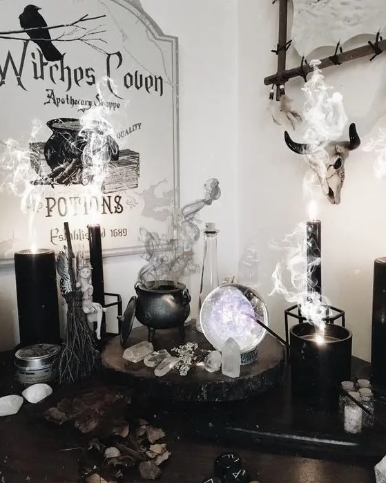 a chic witch's nook with a cauldron with smoke, candles, crystals, a sphere and some signs is a gorgeous idea for Halloween