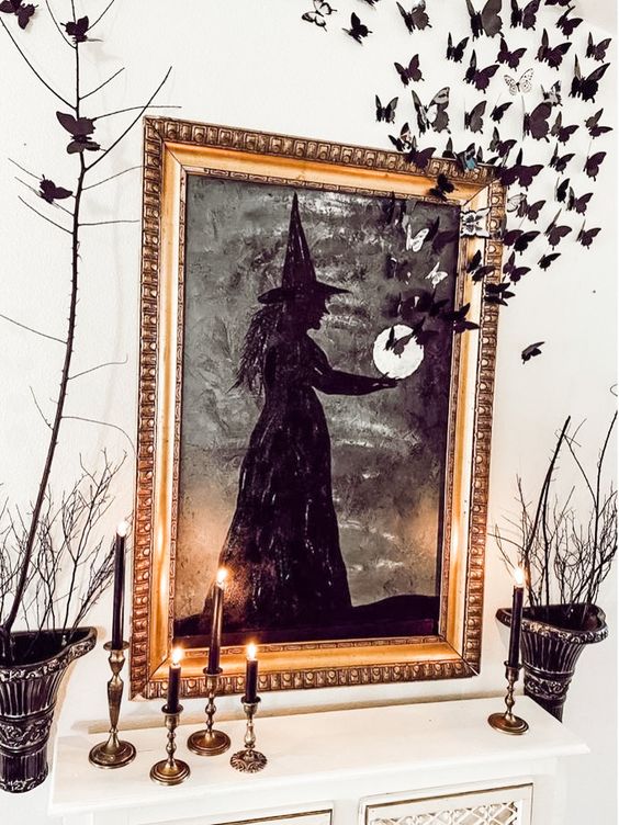 creative and chic Halloween decor with a black witch artwork and butterflies, black candles and branches