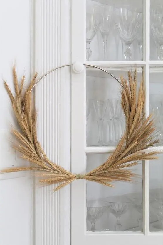 a simple and modern Thanksgiving wreath made of a metal frame and some wheat is a stylish idea for decor
