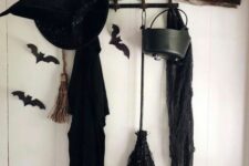 35 style your entryway with a black cloak, a witch’s hat, black bats, a broom and a cauldron and make it Halloween-ready