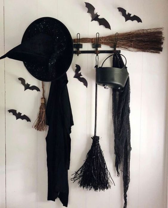 style your entryway with a black cloak, a witch's hat, black bats, a broom and a cauldron and make it Halloween-ready