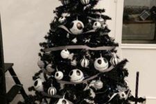 a black Halloween tree decorated with striped and Jack Skellington ornaments, striped ribbon and black brooms
