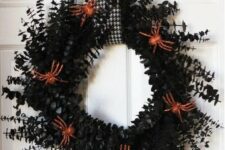 a black foliage wreath decorated with orange glitter spiders, with a printed loop is a lovely decoration for Halloween