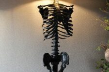 a black skeleton table lamp with a round lampshade is a stylish idea for Halloween decor and it looks scary