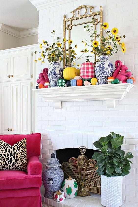 a bold and bright fall mantel with colorful pumpkins, plaid and color block ones plus yellow blooms in vases is amazing