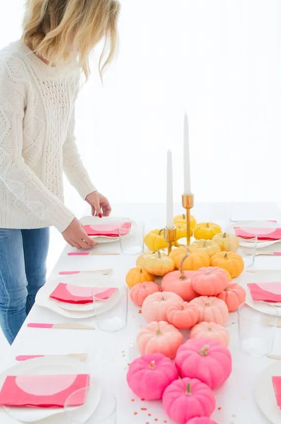 a contemporary fall tablescape in white and with colorful touches - a bold pumpkin table runner and pink napkins