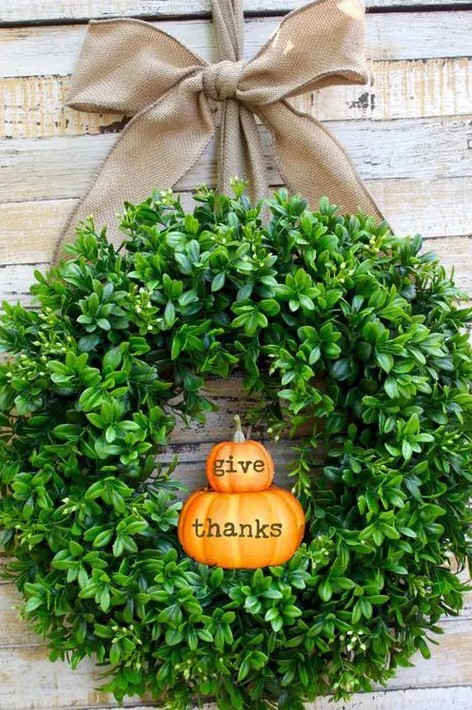a cool and fresh Thanksgiving wreath of boxwood and little pumpkins and a large burlap bow for your front door