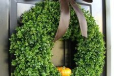 a cute fall or Thanksgiving wreath of fake greenery, a little faux pumpkin and a brown silk ribbon bow