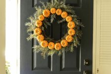 a fall or Thanksgiving wreath with evergreens and bold orange mini pumpkins is a classic idea for the fall