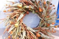 a fantastic harvest Thanksgiving wreath of herbs, leaves, greenery, dried blooms and wheat looks very natural and organic