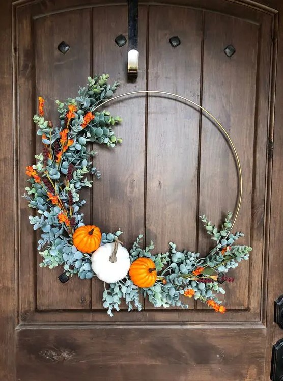 a large and bold fall or Thanksgiving wreath with faux greenery, blooms and a trio of bold pumpkins is a lovely idea