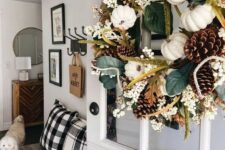 a lovely fall or Thanksgiving wreath with leaves, berries, white pumpkins and pinecones is a stylish decoration