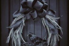 a moody Halloween wreath with dark foliage, a blackbird and a large black bow on top is a lovely decoration