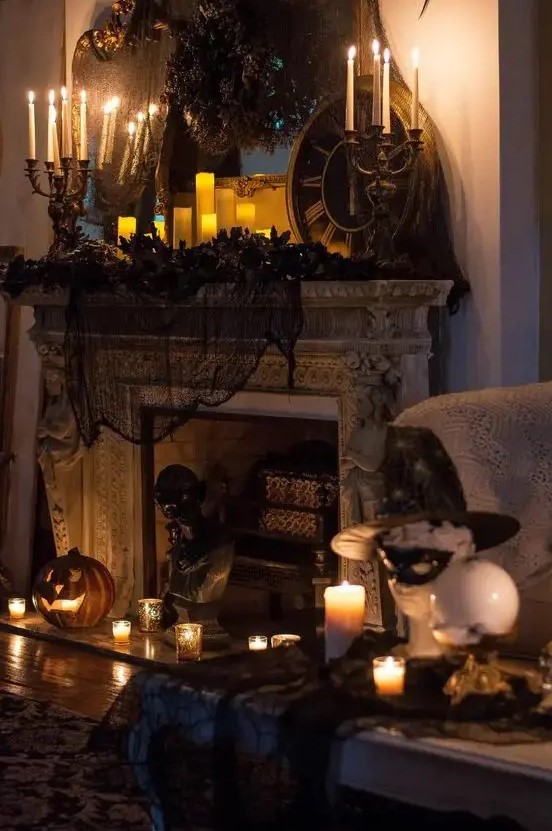 a vintage Halloween fireplace with black spiderweb and pillar candles, vintage candelabras, jack-o-lanterns and black faux blooms