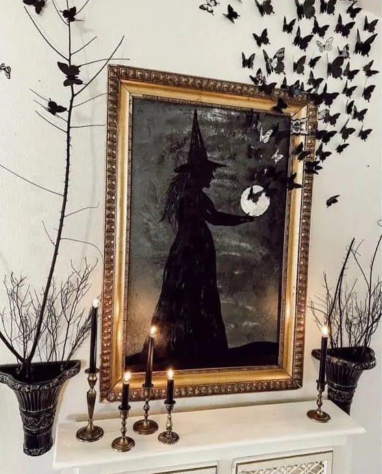 black Halloween decor with candles, black branches with black and white butterflies and a black witch artwork