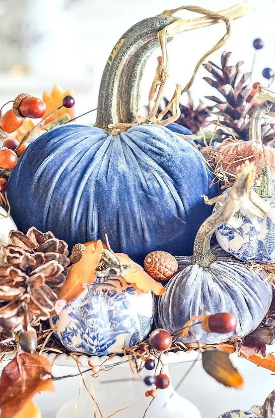 blue velvet and blue floral printed pumpkins stacked with pinecones, acorns and berries compose a gorgeous fall centerpiece