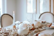 02 a beautiful Thanksgiving tablescape with white candles and pumpkins, grey plates and neutral linens, wooden candleholders and berries