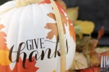 02 a beautiful white pumpkin with decoupaged fall leaves on it and a yellow ribbon is a chic decoration for Thanksgiving