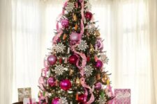 02 a bold Christmas tree decorated with pink and pink sequin ornaments, pink ribbons, lights and large snowflakes and a large star on top
