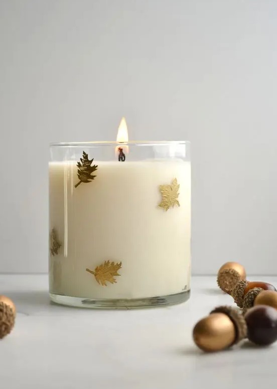 a glass candle with tiny gold leaves attached on the outside is a beautiful fall and Thanksgiving decor idea