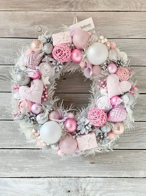 a beautiful pastel pink and silver Christmas wreath with hearts, ornaments, snowy pinecones, fluffs and yarn balls is amazing