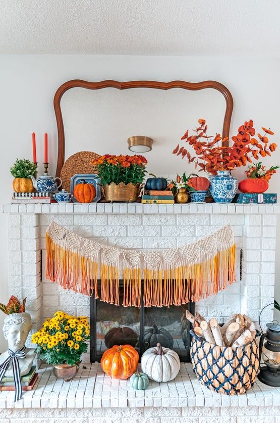 a bright fall mantel with bold blooms, potted greenery, orange, grey and neutral pumpkins, colorful fringe and some bold books