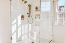 03 an airy and light-filled bathroom done in neutrals, with a shower space enclosed in glass and brass fixtures is beautiful