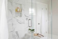04 a contemporary white bathroom clad with marble and herringbone tiles, with a shower with glass doors and neutral fixtures