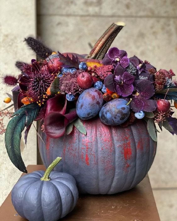 a gorgeous purple and red pumpkin decorated with plum and deep purple blooms, berries and fruits, bunny tails and foliage
