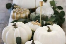 05 a Thanksgiving centerpiece of white and gilded pumpkins, leaves and candles in gold candelholders is a stylish idea