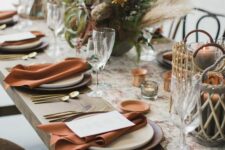 05 a boho Thanksgiving table setting with a lush greenery, pampas grass and willow, rust napkins and gold cutlery