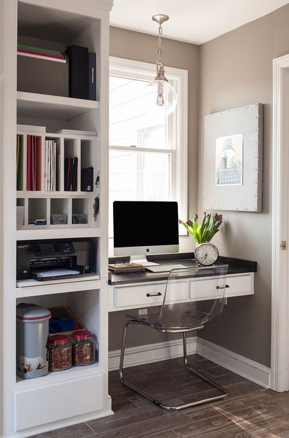 a home office nook squeezed into a small space, with a built-in storage unit and a desk, a clear chair and a pendant lamp
