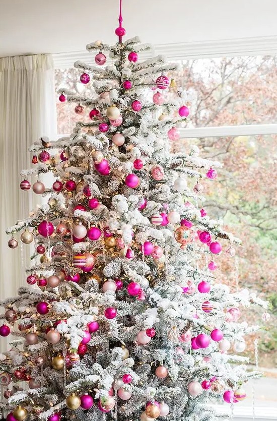 a flocked Christmas tree decorated with neutral, hot pink and blush ornaments and lights looks glam, chic and very modern