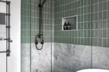 07 a modern bathroom with white marble and green tiles, an oval tub, a shower space with clear glass seamless doors
