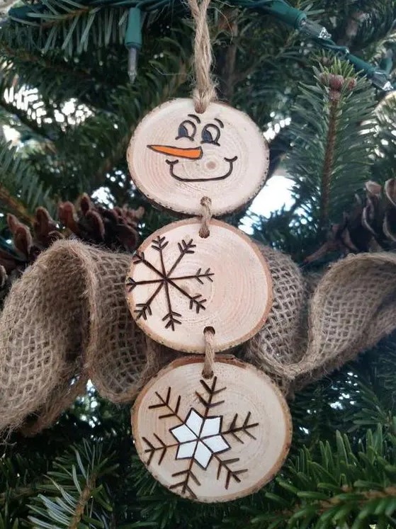 a wood slice snowman with wood burnt snowflakes and a face is a cool rustic Christmas ornament to rock