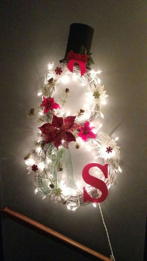 a Christmas wreath shaped as a snowman, with a red monogram, snowflakes and fabric blooms plus a top hat