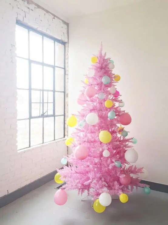 a hot pink Christmas tree decorated with balloons of various colors is a super fun and bold idea for celebrating