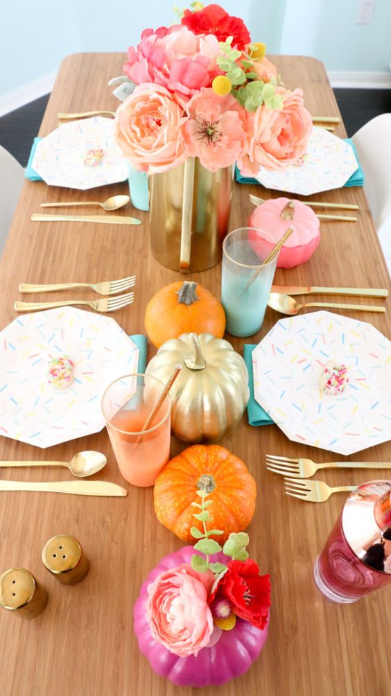a bold modern Thanksgiving tablescape with bright pumpkins and blooms, confetti plates and colorful glasses