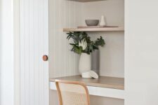 12 a small and clean working nook with a couple of built-in shelves and a desk, a woven chair, potted greenery and decor
