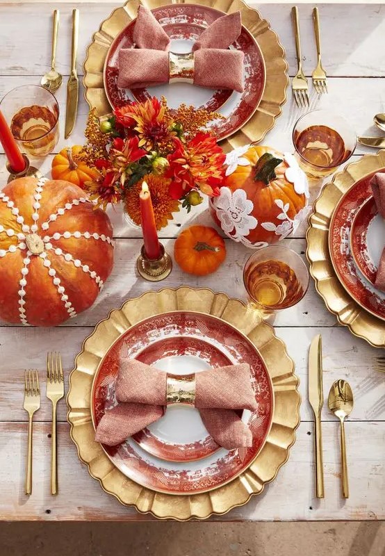 a bright and whissy Thanksgiving tablescape with gold chargers, cutlery, colorful pumpkins and floral arrangements, bold candles
