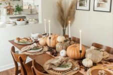 13 a neutral and very cozy Thanksgiving tablescape with a large runner and woven placemats, natural pumpkins and tall and thin candles