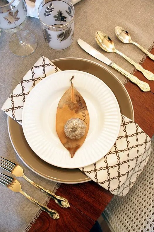 a brown leaf and a gold glitter pumpkin for marking a place setting at Thanksgiving